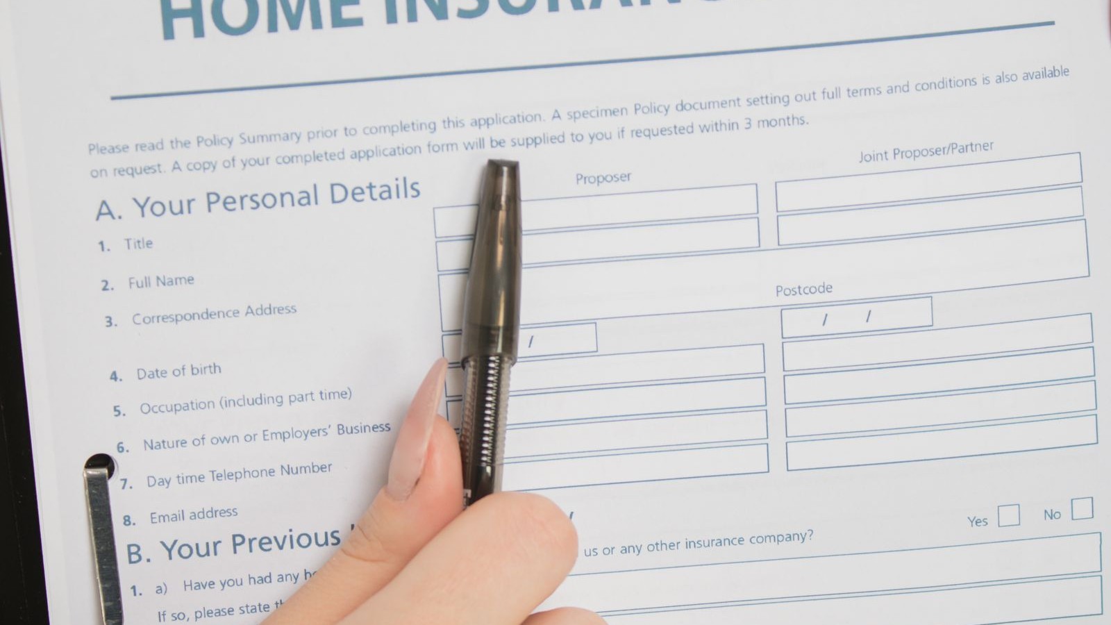 A hand holding a printed document with a pen, resting on a table