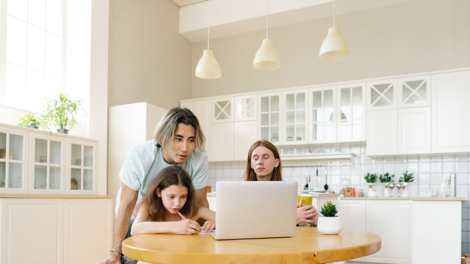 A family learning together around a laptop in a bright kitchen