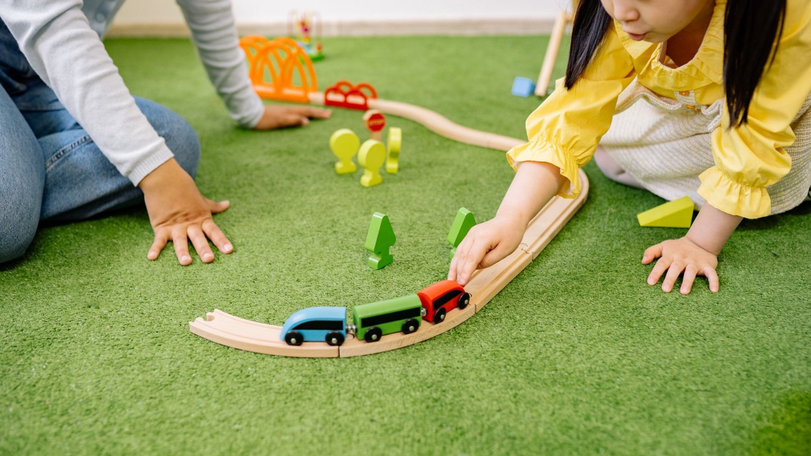 木の電車のおもちゃで遊ぶ子ども