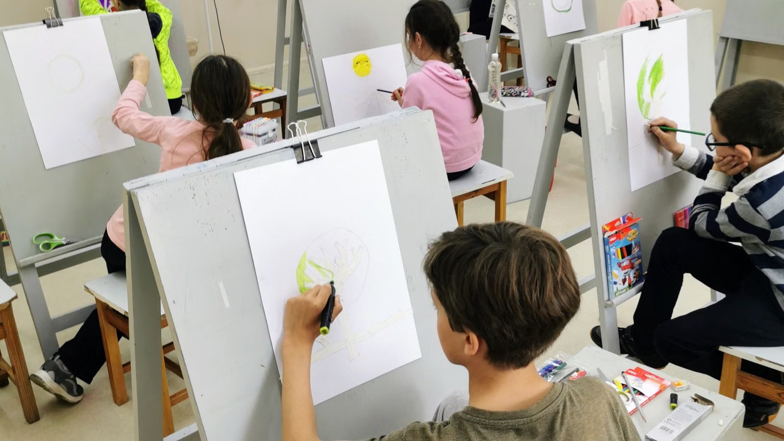 イーゼルに向かって絵を描く子どもたち