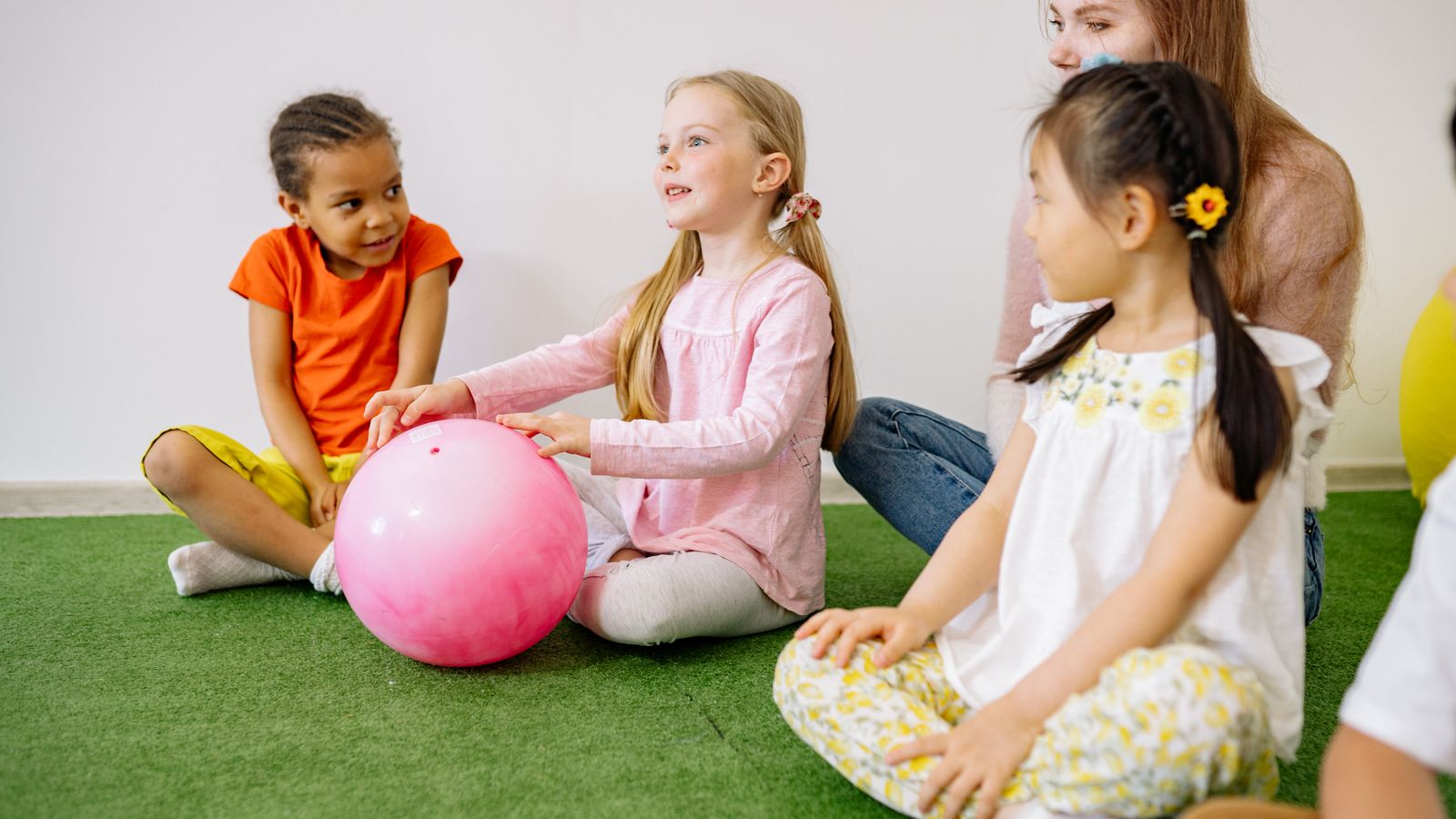 ピンクのボールを囲んで遊ぶ子どもたち
