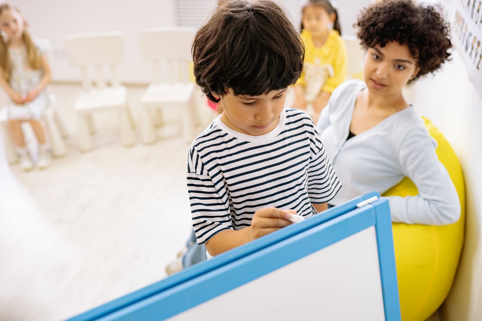 先生のそばでタブレットを使って学ぶ男の子