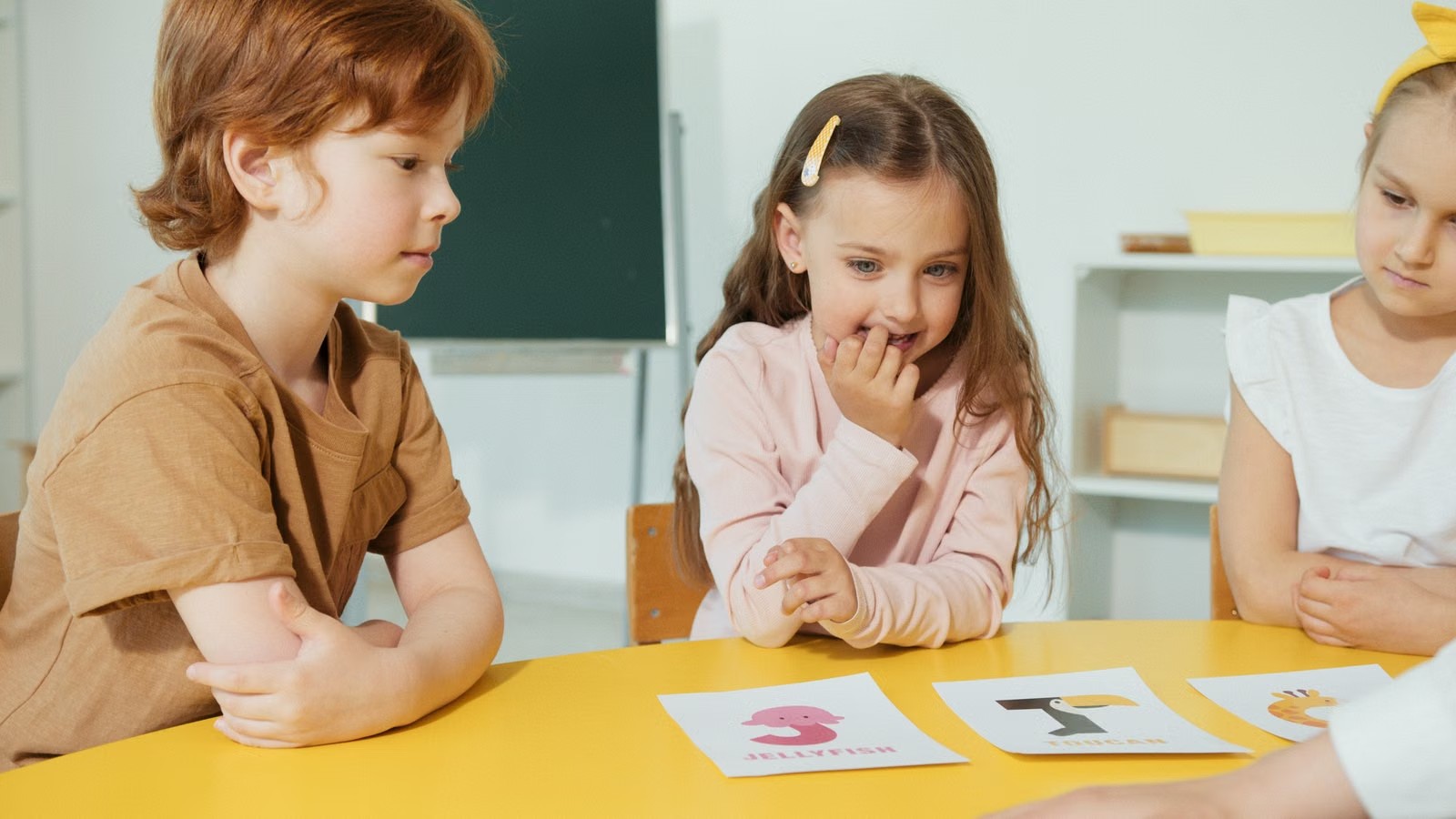 テーブルを囲み、カードを使って英語を学ぶ子どもたち