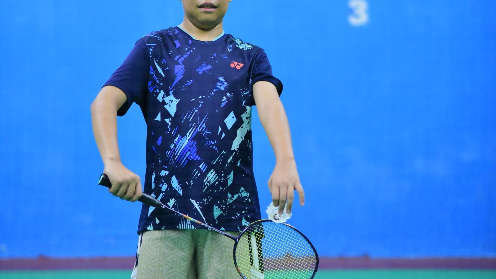 体育館でバドミントンのラケットを構える男の子