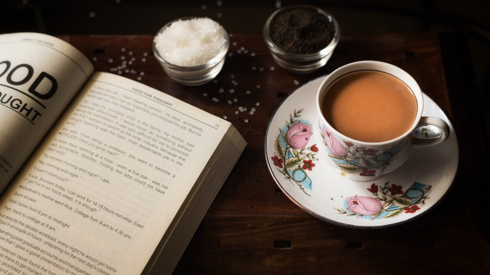 開いた本のそばに置かれた、温かいお茶のカップ