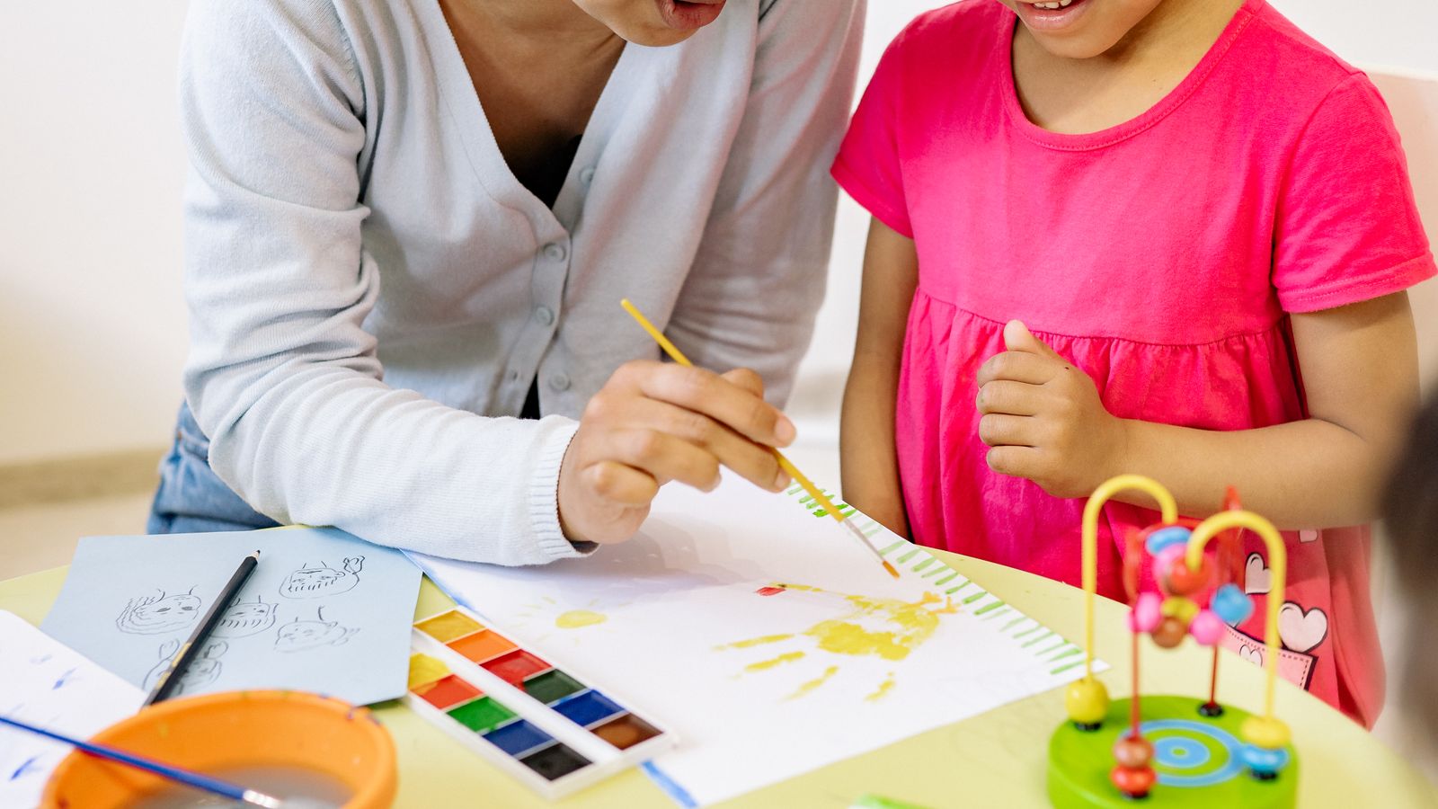 先生と一緒に絵の具で絵を描く子ども