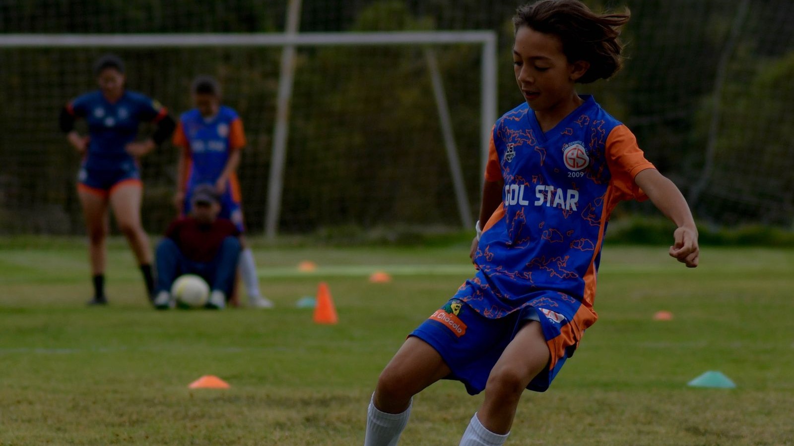 サッカーボールを追って練習する子ども