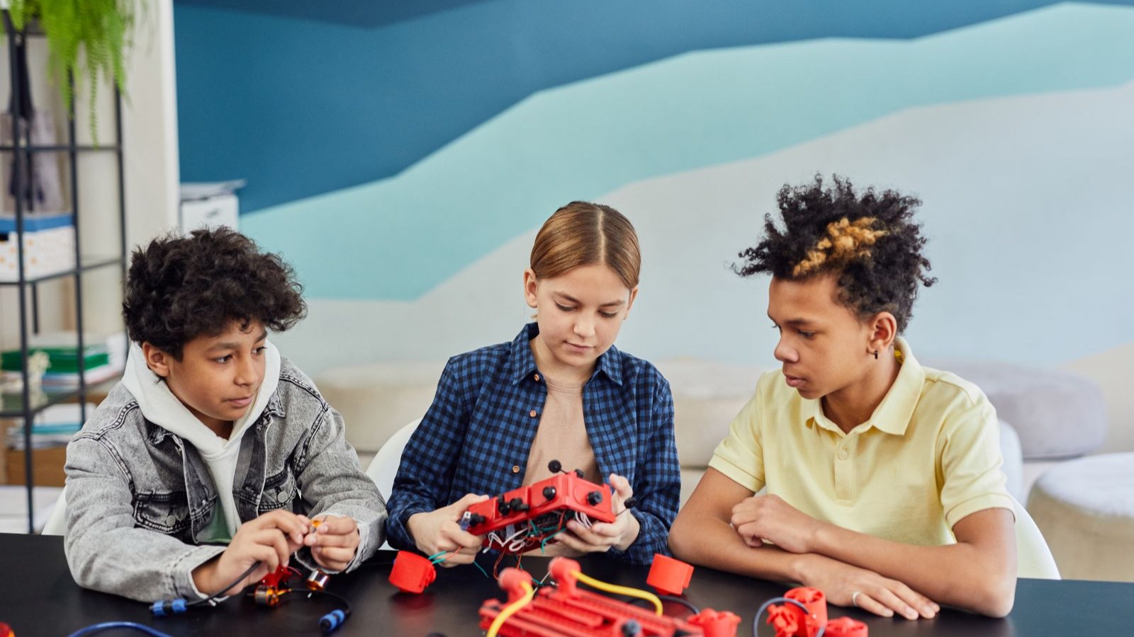 先生と子どもたちが一緒にロボットを組み立てている教室の様子