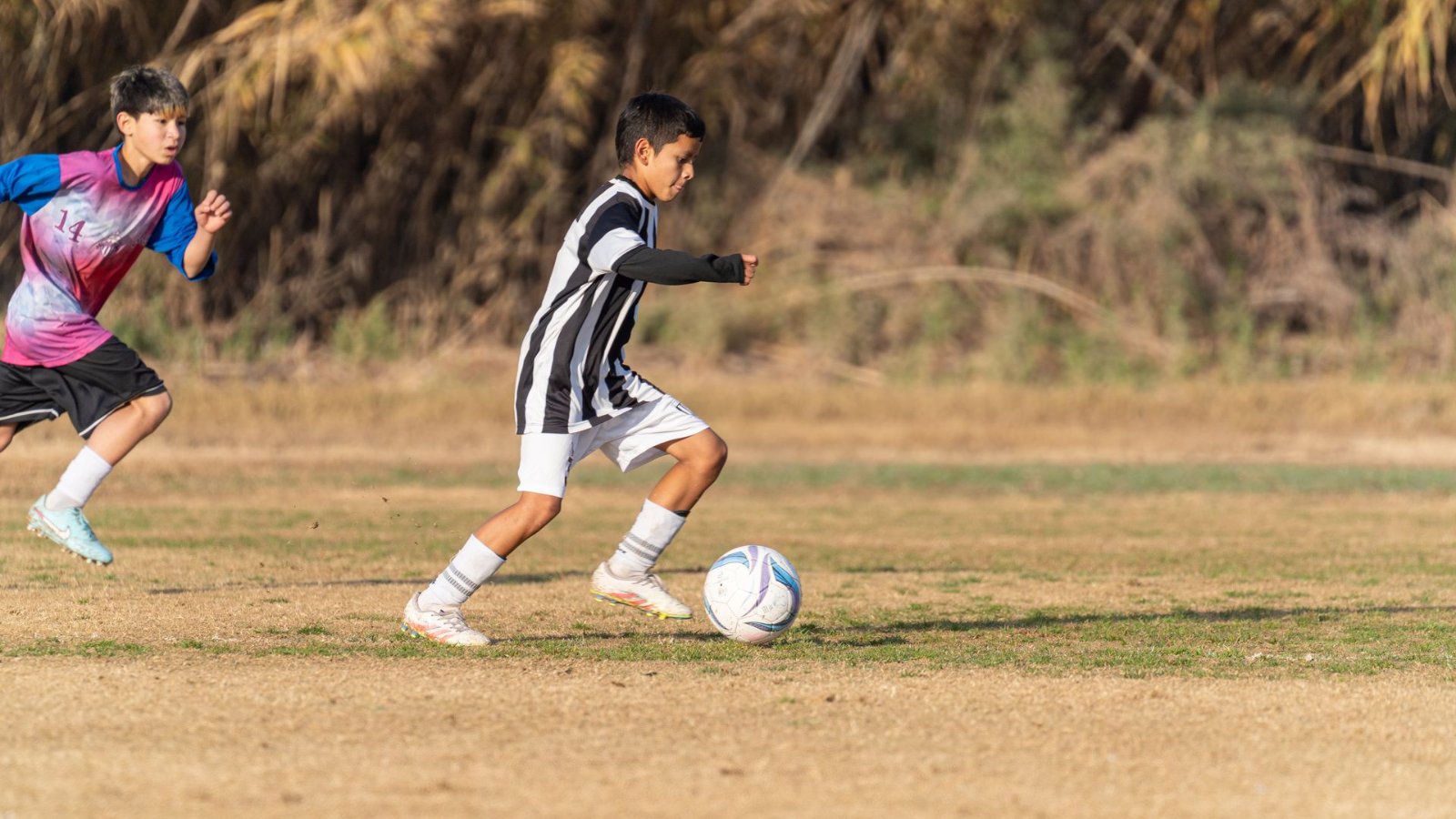 校庭でサッカーボールを蹴る男の子