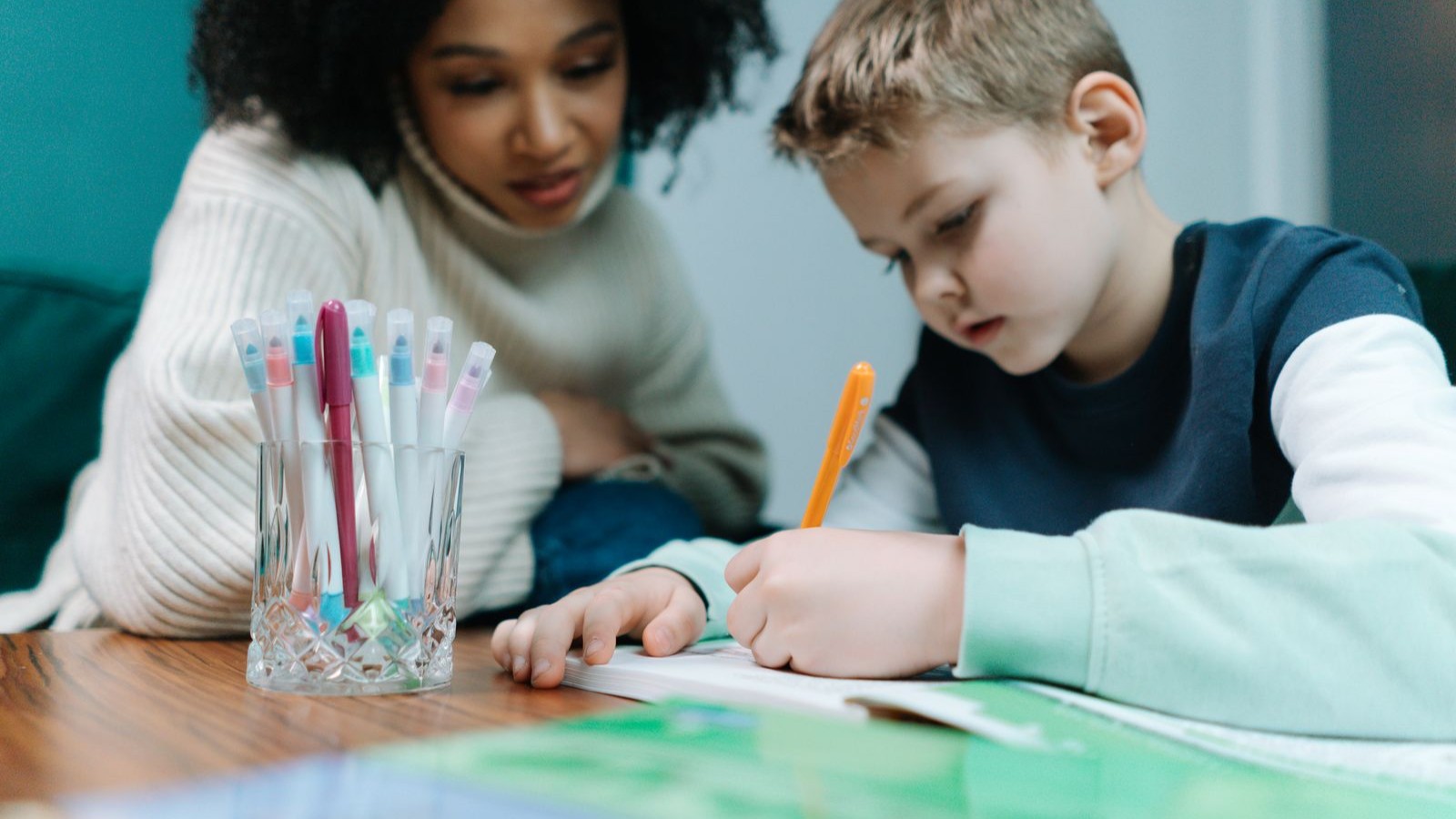 先生に見守られながら机で書き取りをする子ども