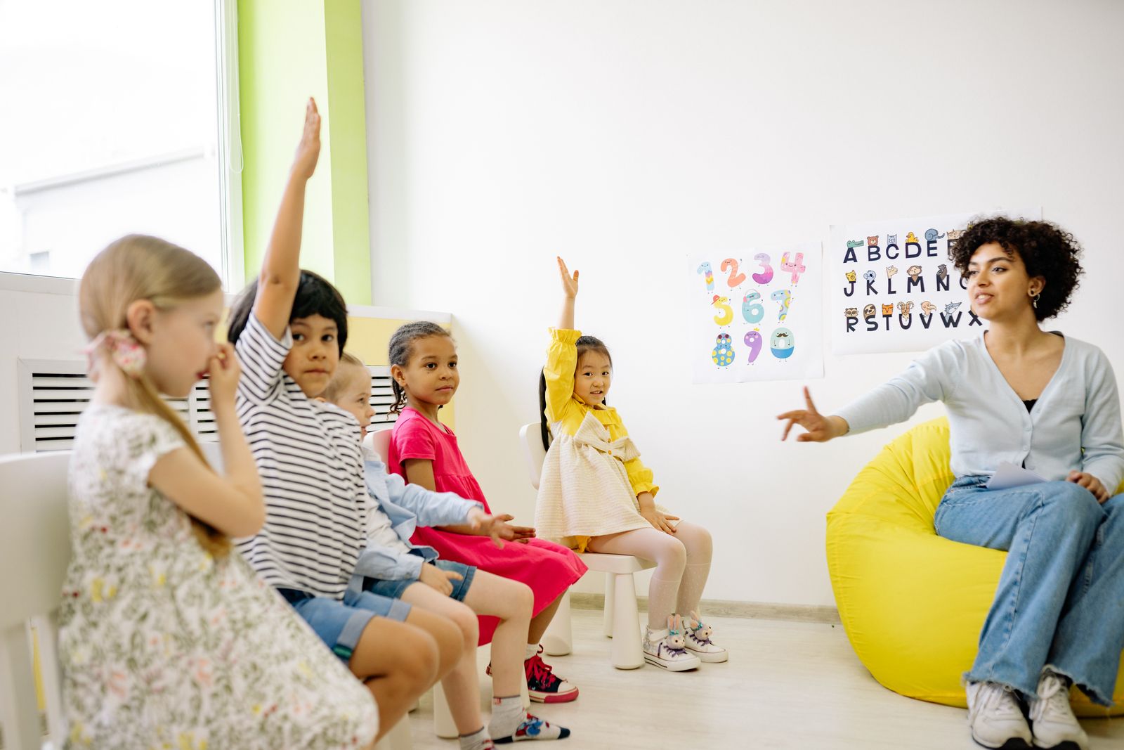 教室で先生に向かって手を挙げる子どもたち