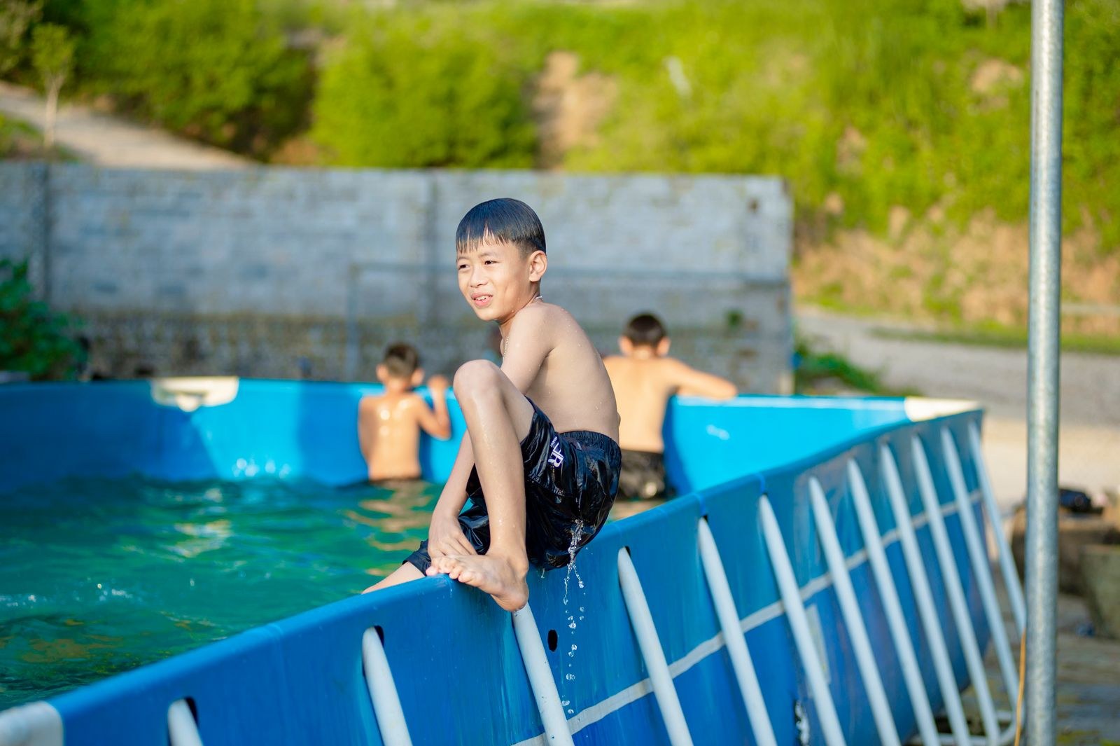 プールのふちに座る笑顔の男の子（水泳）