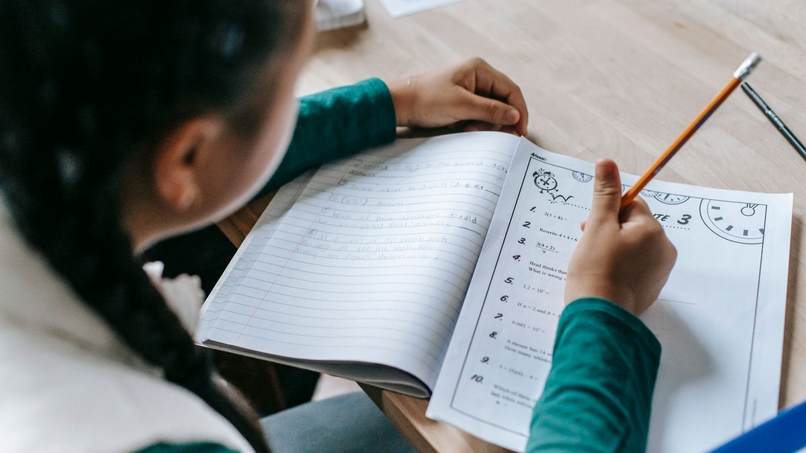 A child writing in a practice notebook with a pencil