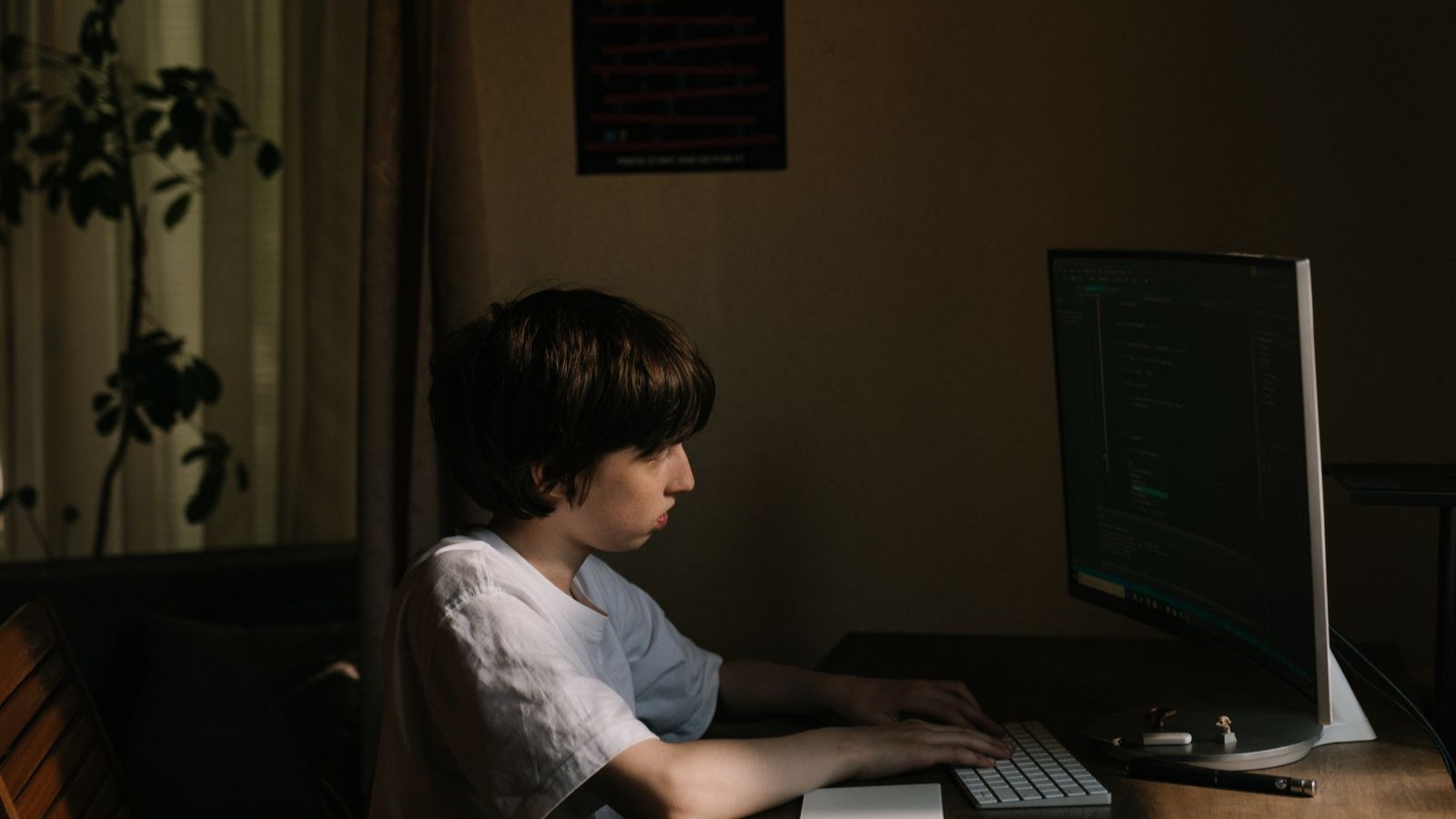 自宅のパソコンに向かってプログラミングをする10代の男の子