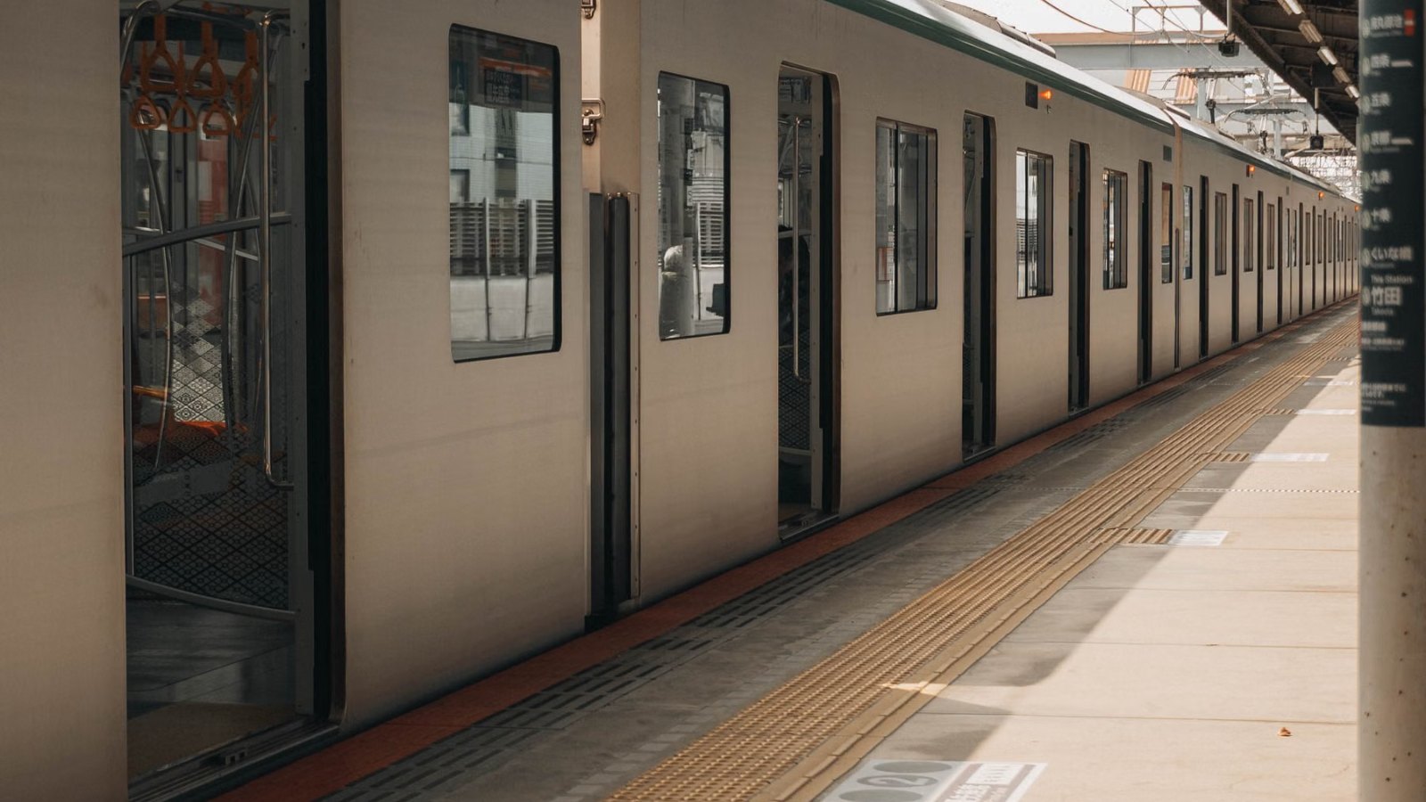 日中の屋根付きホームに停まる人のいない電車