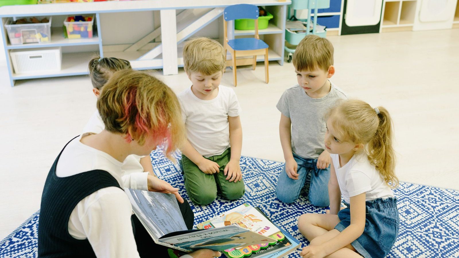先生の読み聞かせを囲んで座る子どもたち