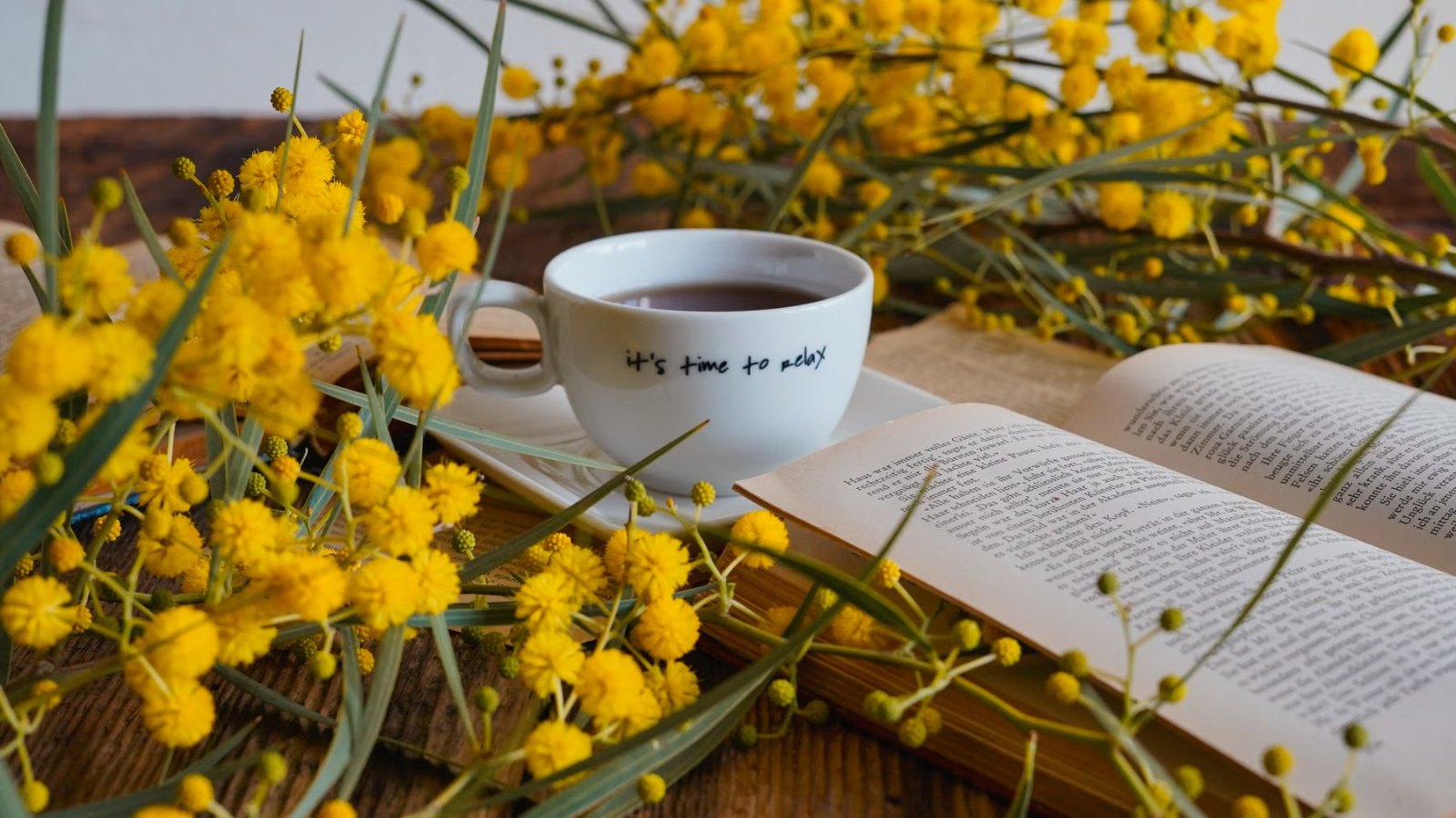コーヒーカップとミモザの花、開いた本