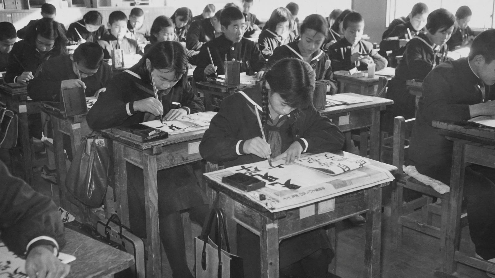 教室で書道に取り組む子どもたち(モノクロ写真)