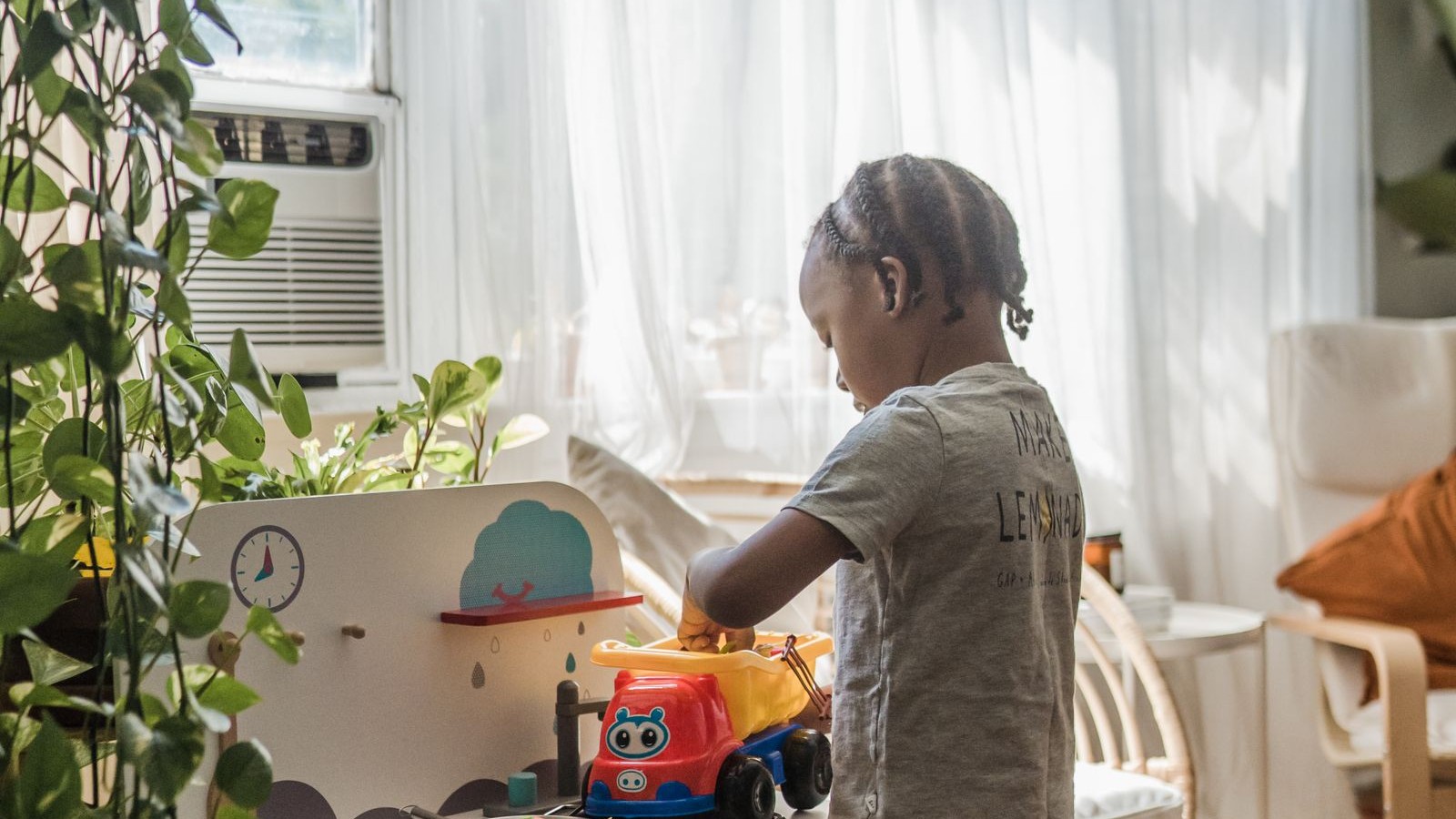 A child playing alone with toys on the floor of a living room at home