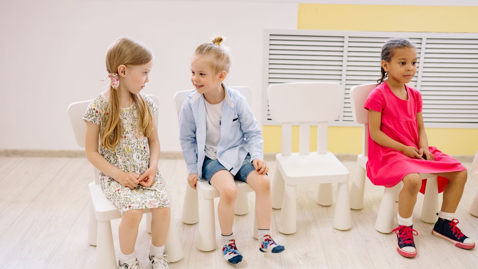Several children sitting together and talking in a bright classroom