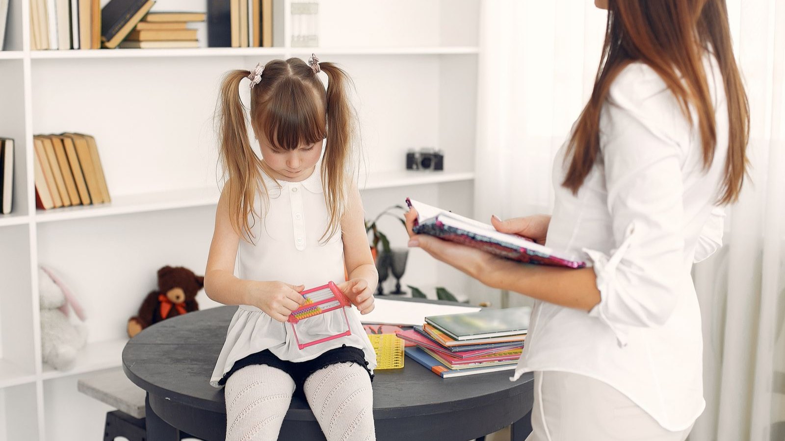 先生と一緒に机で勉強に取り組む子ども