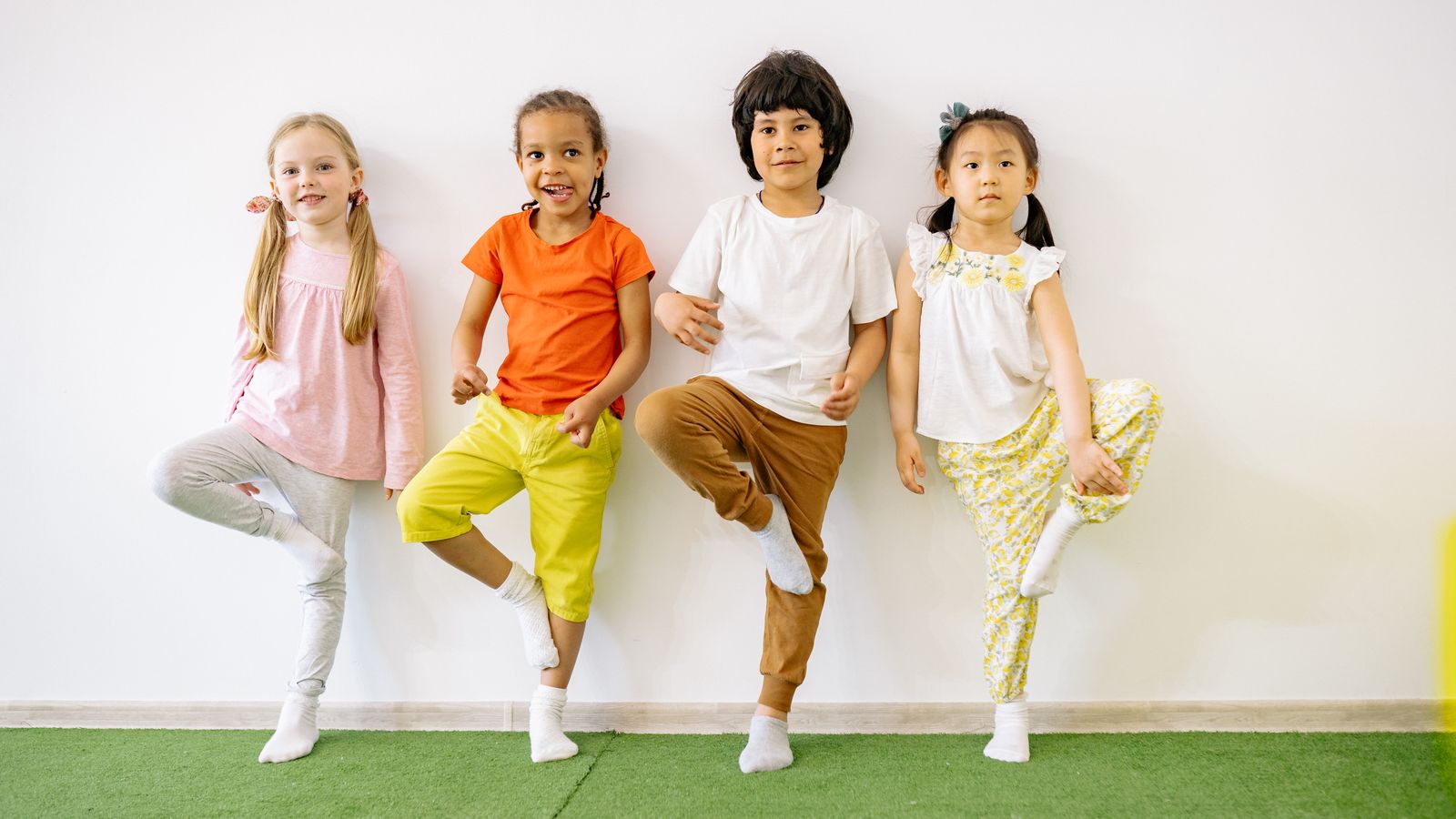壁にもたれて片足立ちをする4人の子どもたち