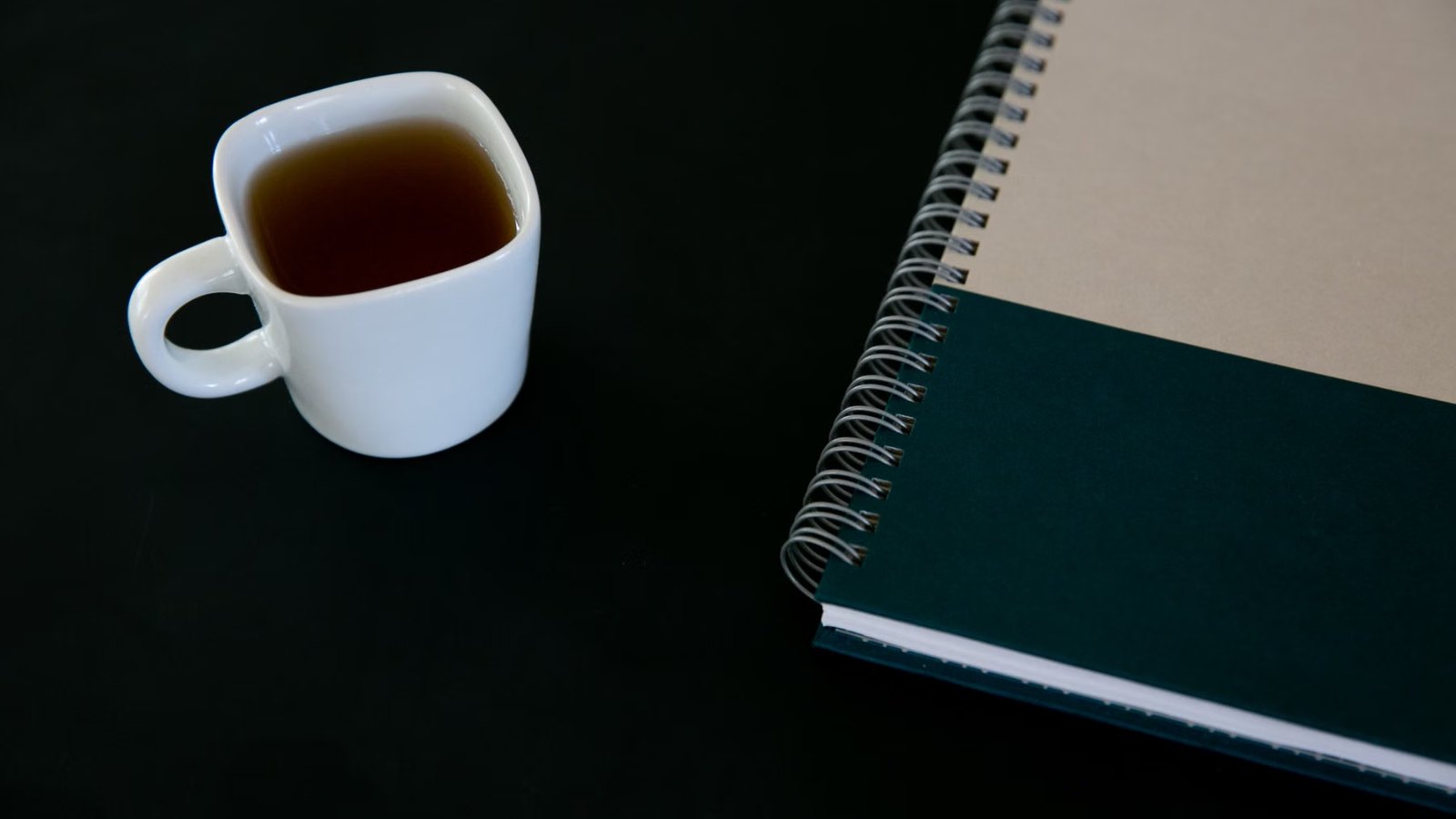 湯気の立つお茶と開いたノートのある朝のテーブル