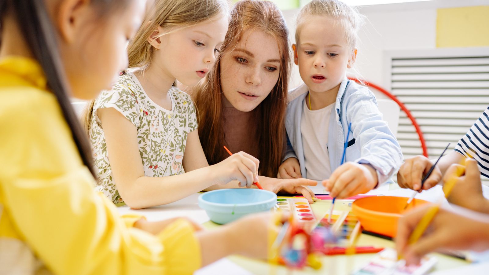 子どもたちが先生と一緒に机で学んでいる様子