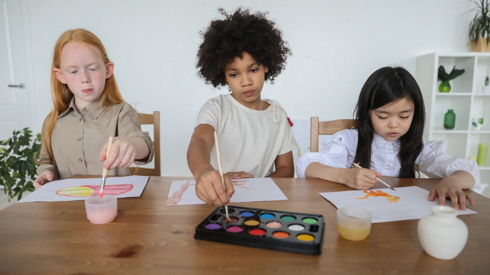 テーブルで水彩絵の具を使って絵を描く子どもたち
