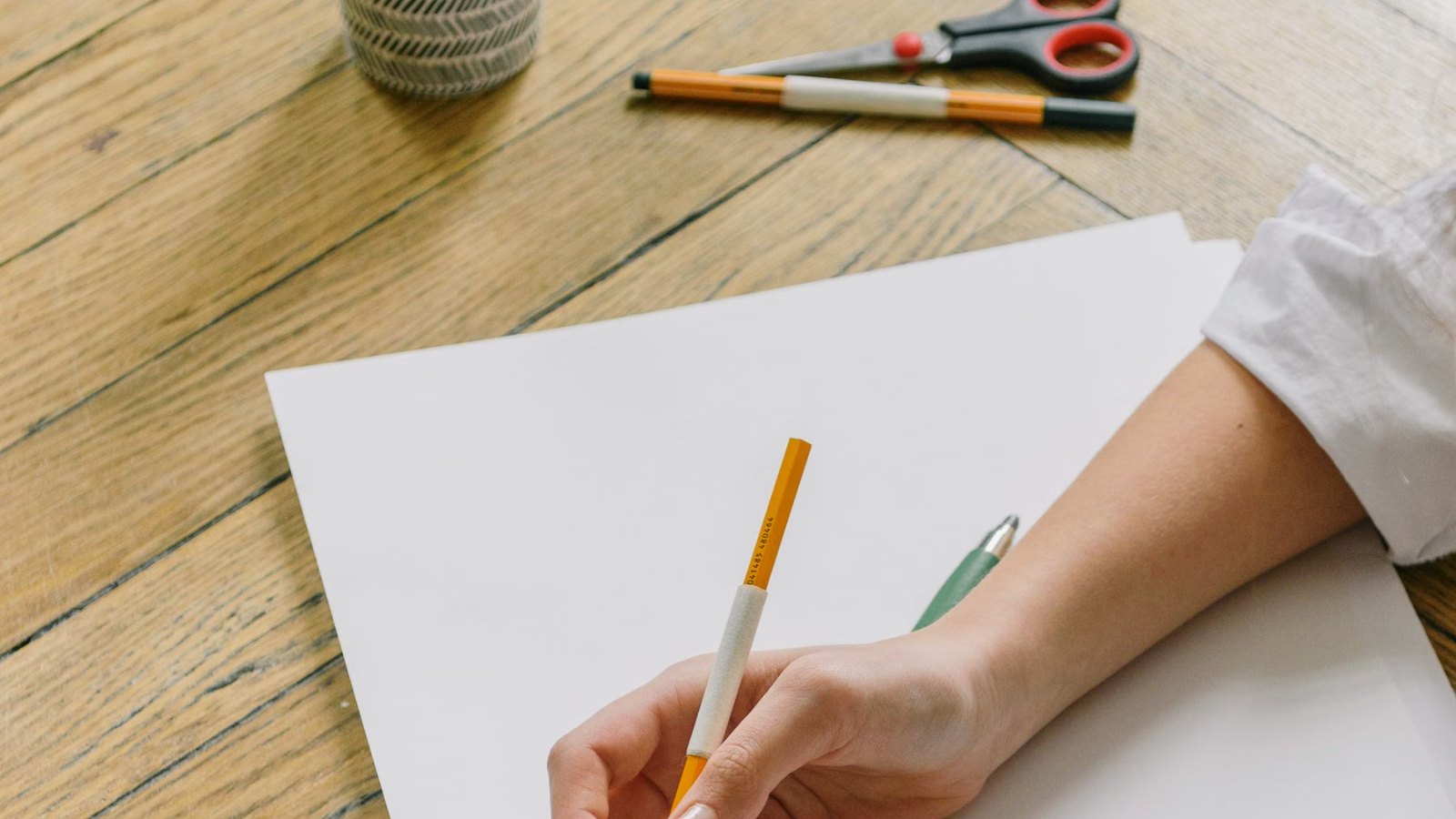 白い紙に鉛筆で絵を描く手元