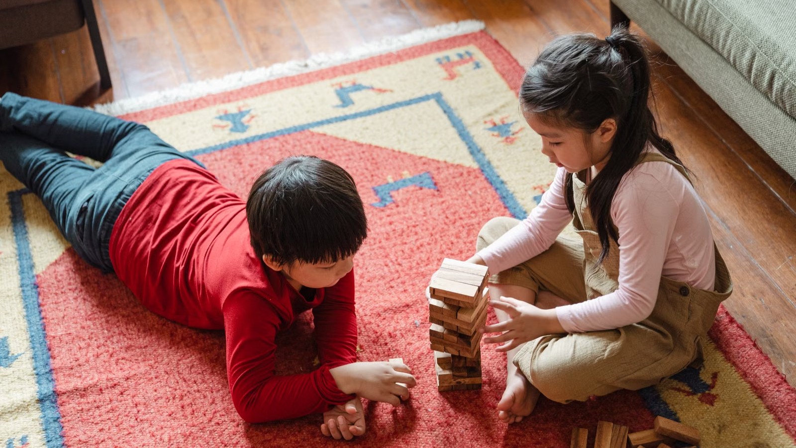 Two siblings of primary-school age playing together on the floor of a bright living room