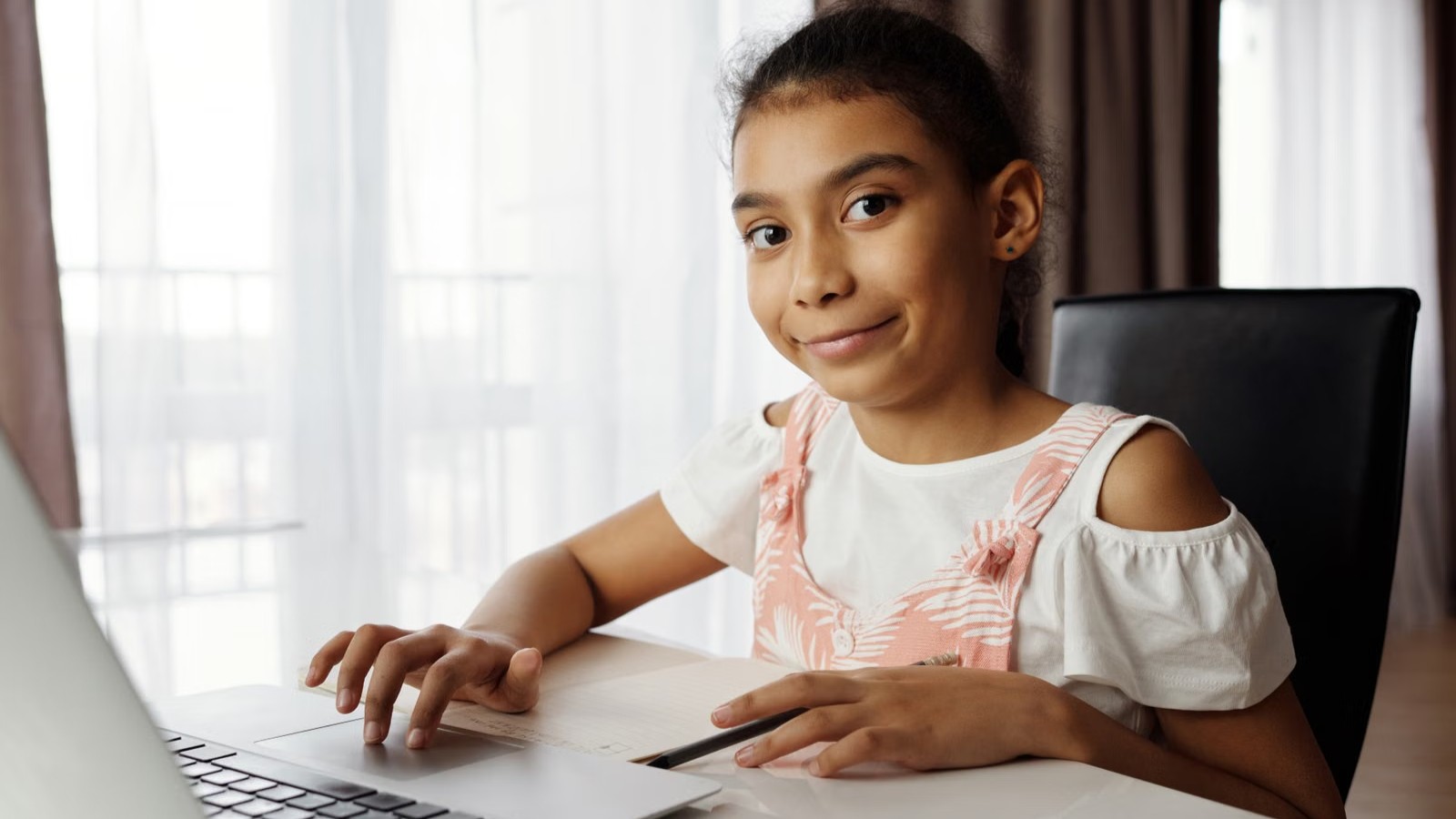 A child smiling during an online class at home with a laptop