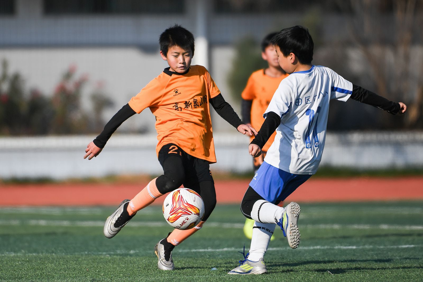 校庭でボールを追ってサッカーをする子どもたち