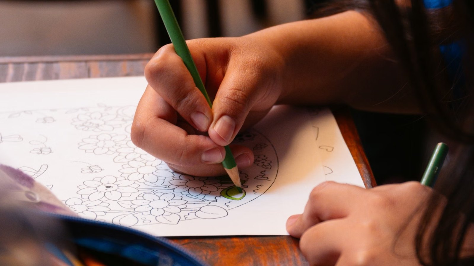 色えんぴつを持って、ノートに絵を描き込む子どもの手