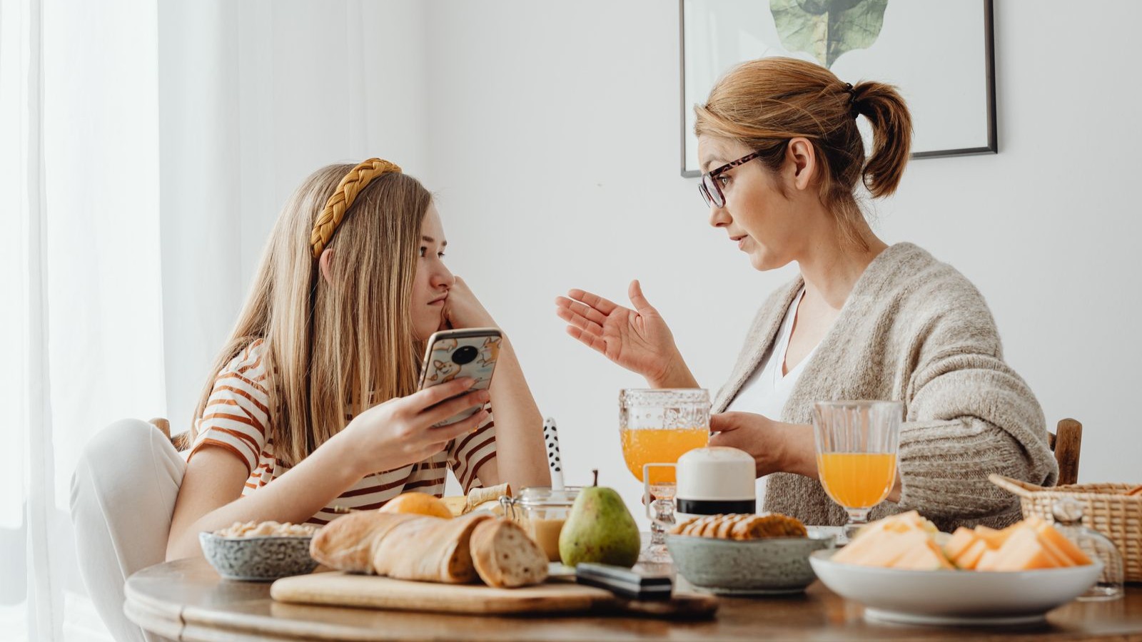 A parent and a teenager talking at a kitchen table