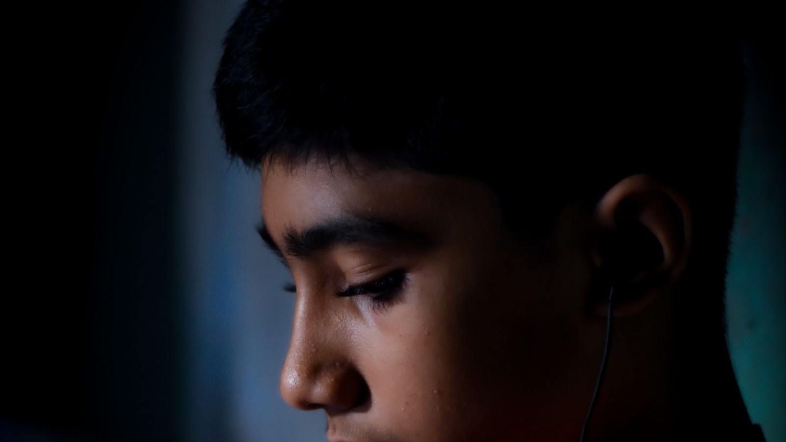 A teenager wearing headphones looking out of a window