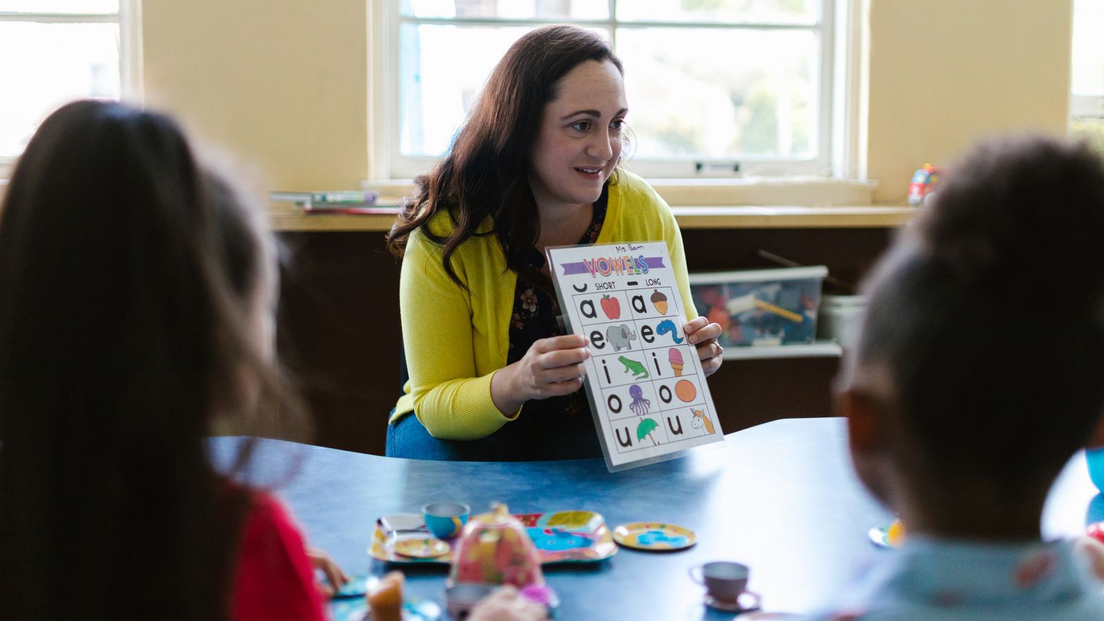 先生と一緒に英語のカードを使って学ぶ子どもたち(イメージ)