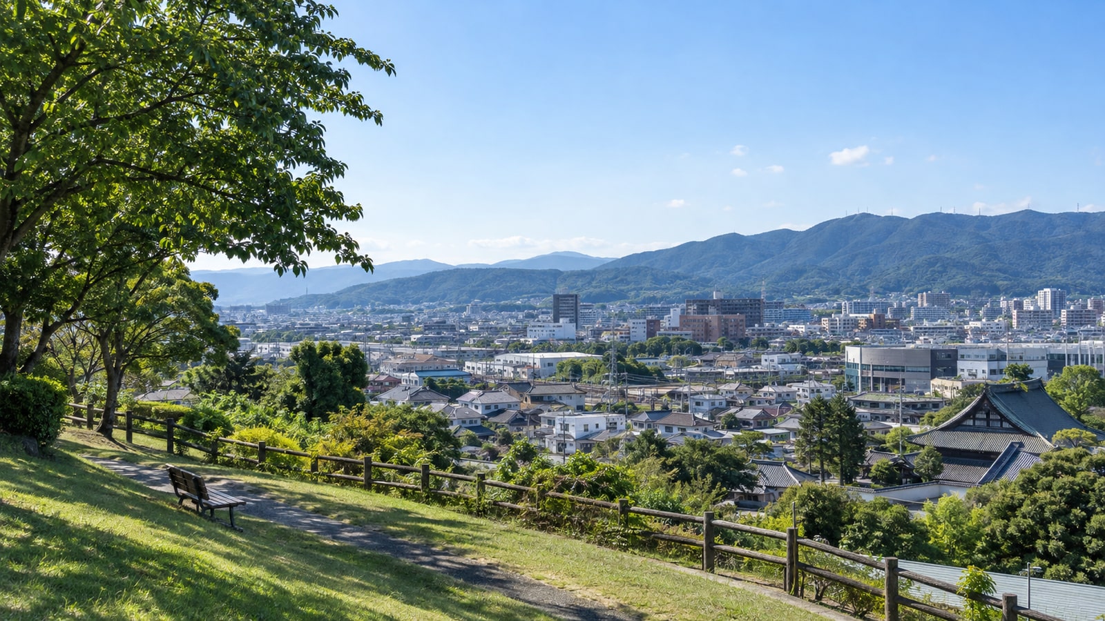 豊川市の寺社の屋根と山並みを望む明るい街の風景