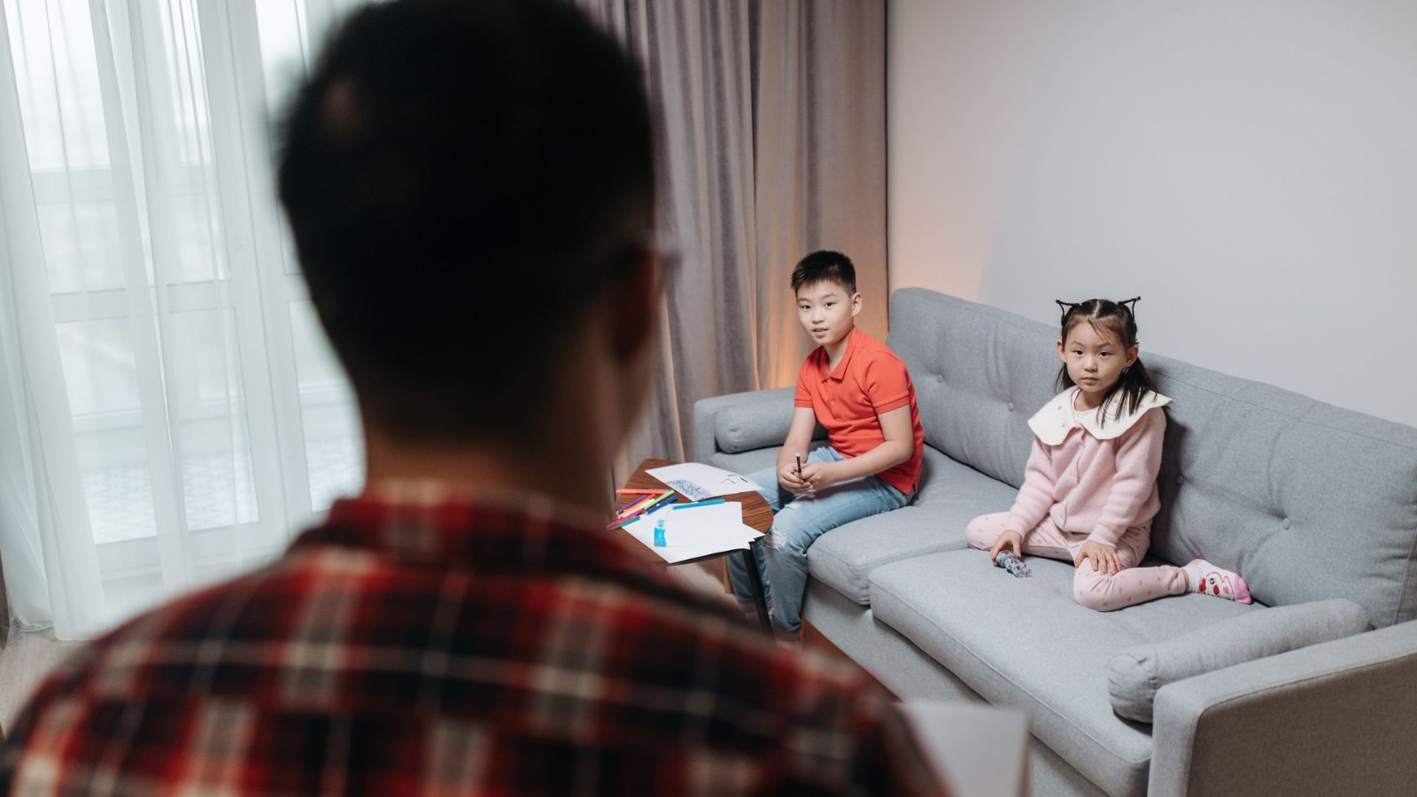 ソファに座る子どもたちと話す父親