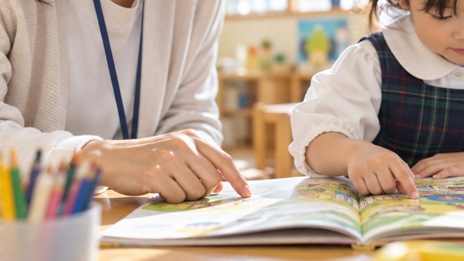 絵本を一緒に読む保育者と子ども