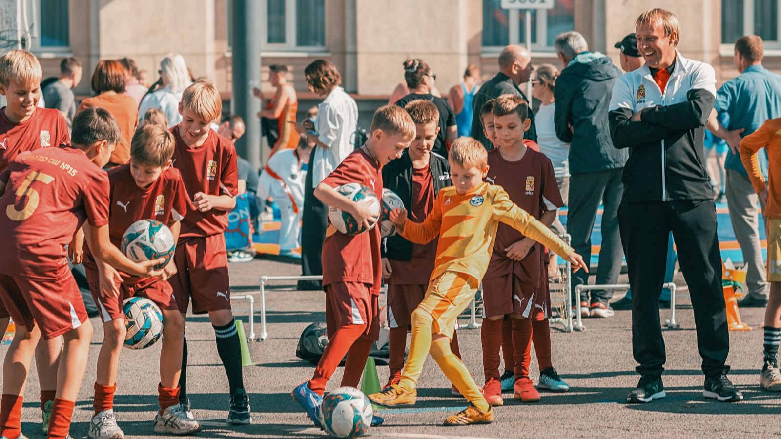 サッカーボールを追う子どもたちとコーチ