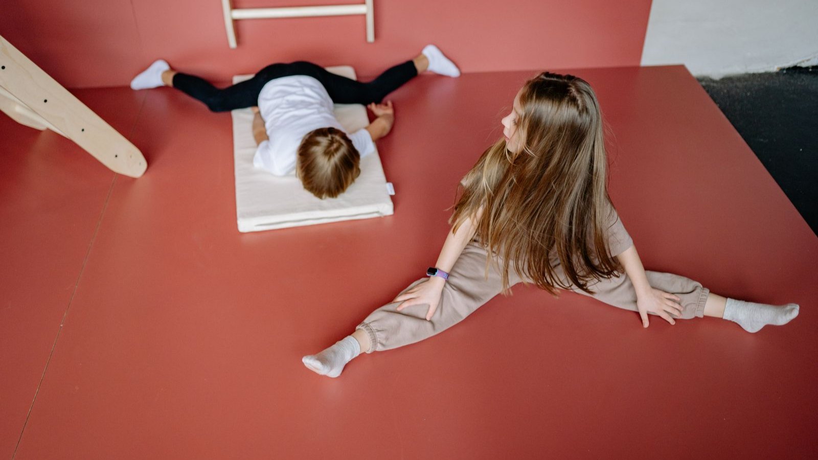 赤いマットの上で体操のストレッチをする子どもたち